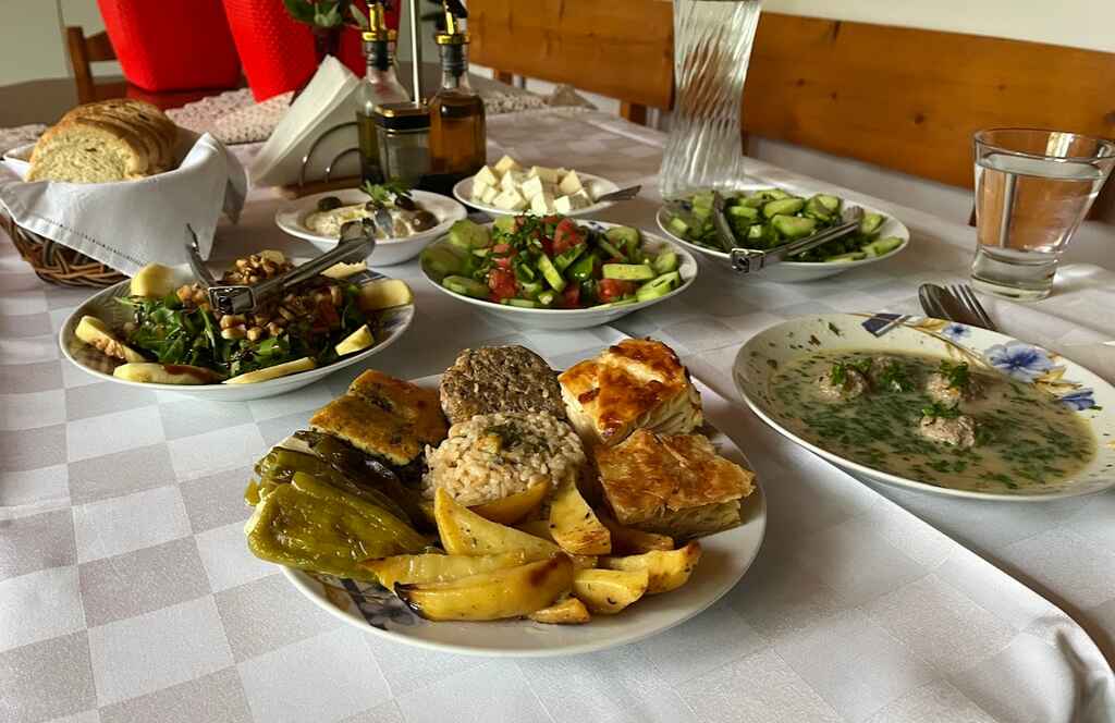 Albanian Food on table - stuffed peppers, qofte or meatballs, soup, byrek and potatoes, salad